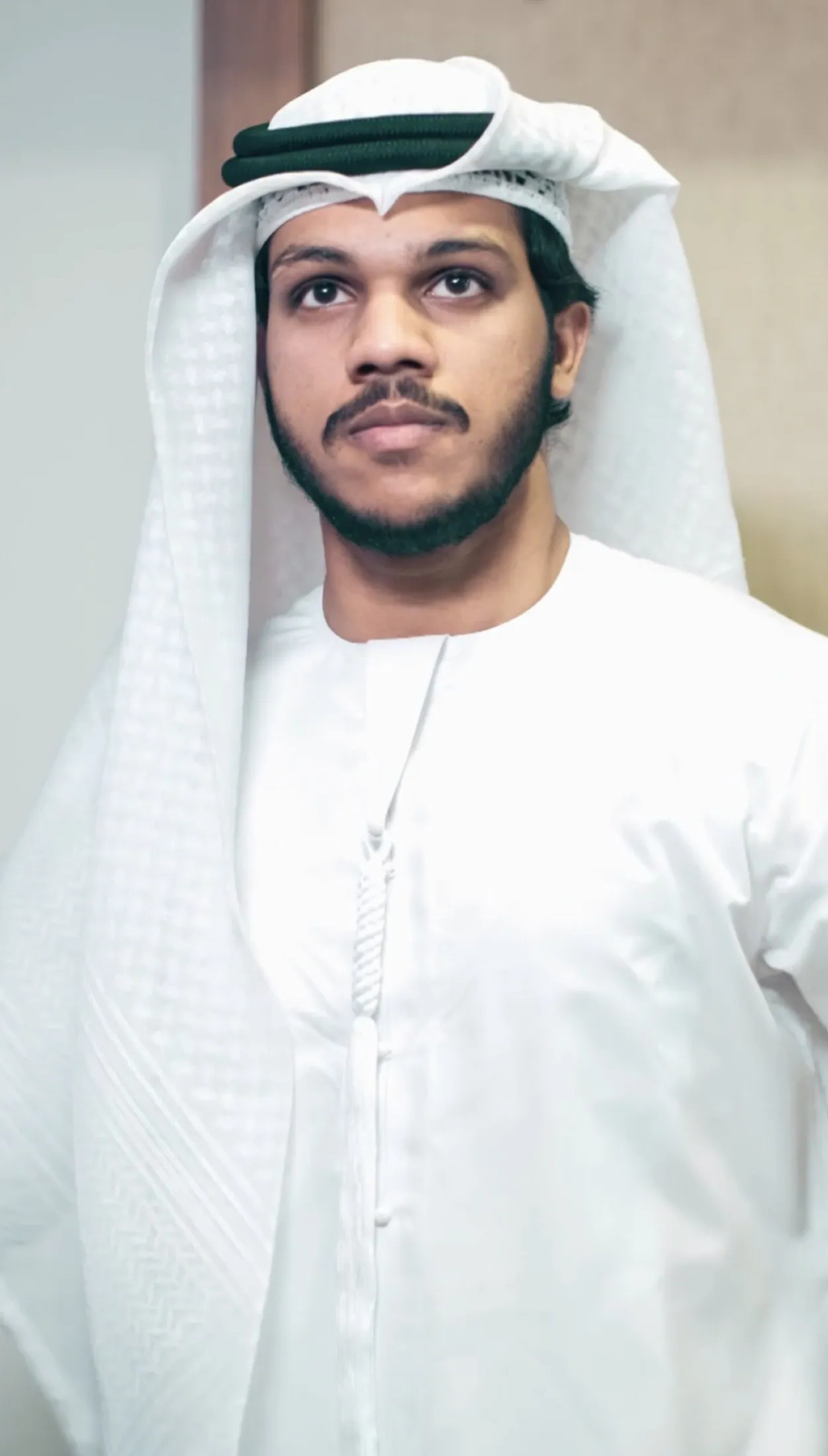 Portrait of Muhammed Shafad in a white kandura, looking away from the camera