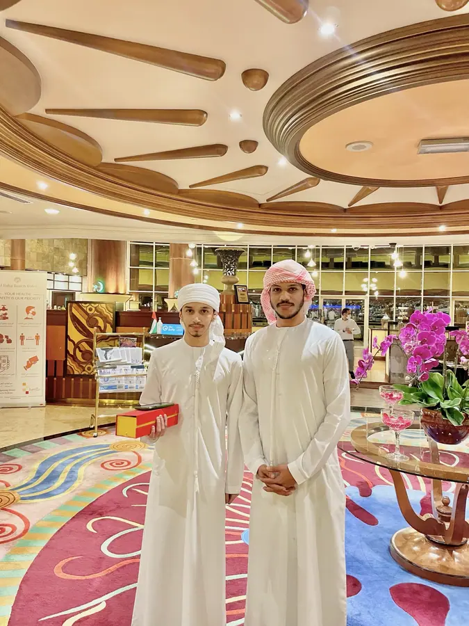 Two men in kandura standing in an ornate hall