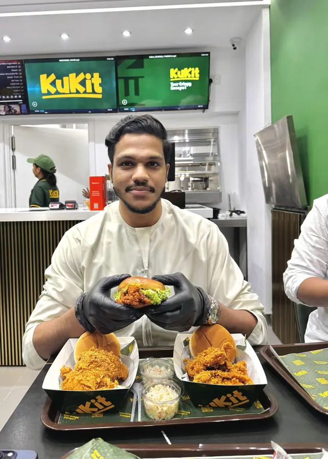 Muhammed Shafad holding fried chicken inside the Kukit outlet in Ajman